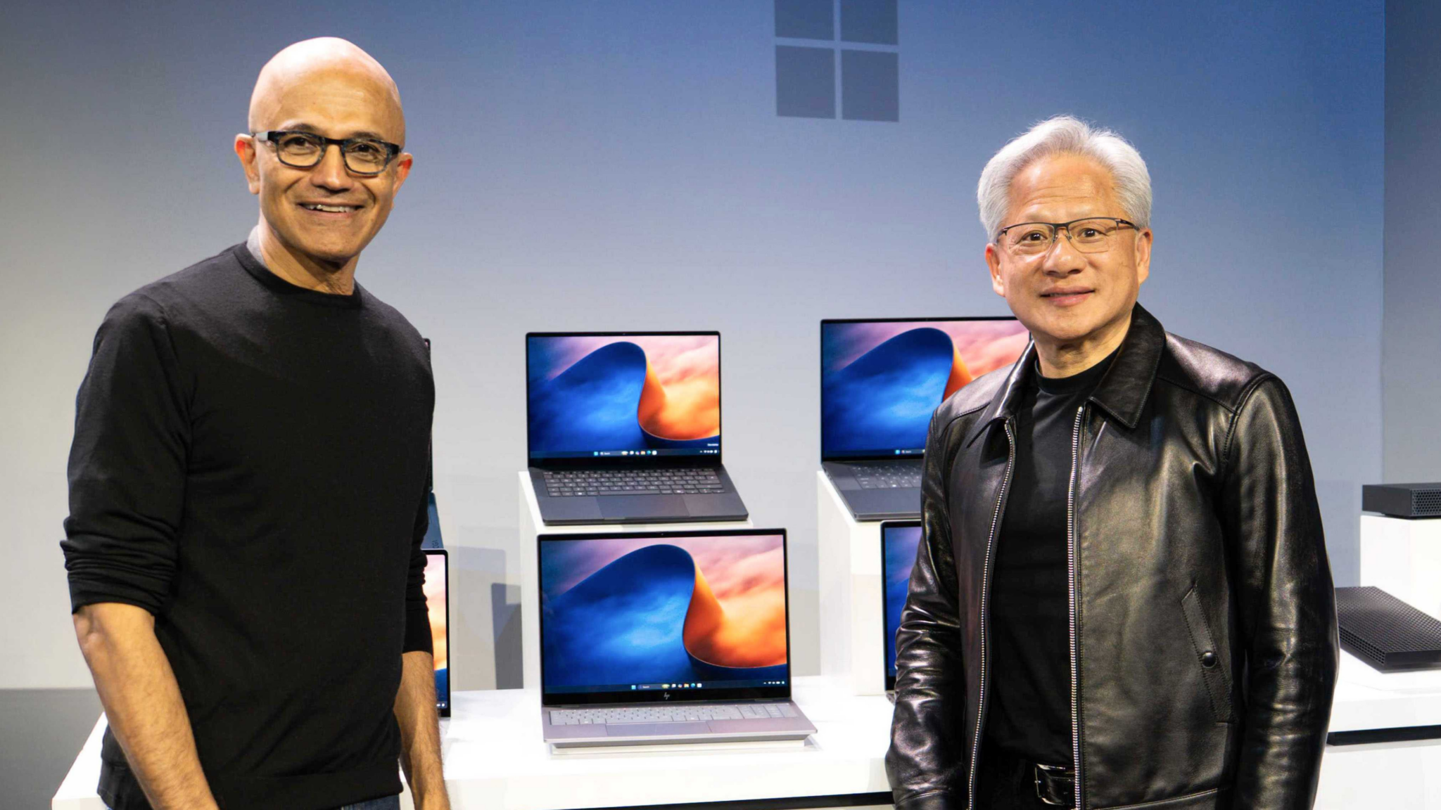 Satya Nadella and Jensen Huang standing in front of RTX Spark laptops on display at the October 7 Windows event